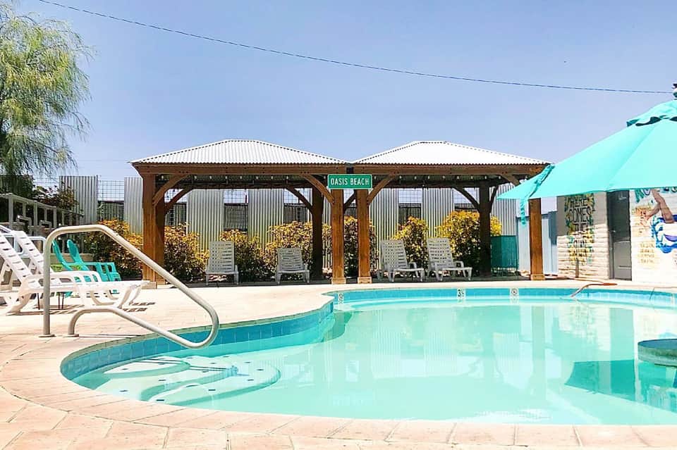 Resort swimming pool with turquoise water, covered pavilion, and lounge chairs on sunny patio