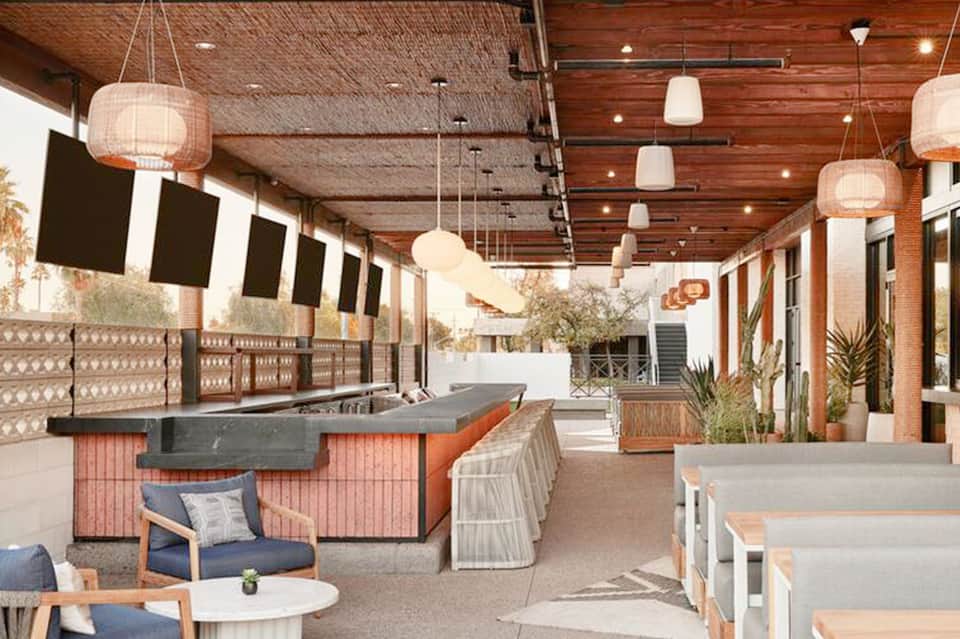 Modern rooftop bar and lounge with wooden ceiling, pendant lights, and seating areas