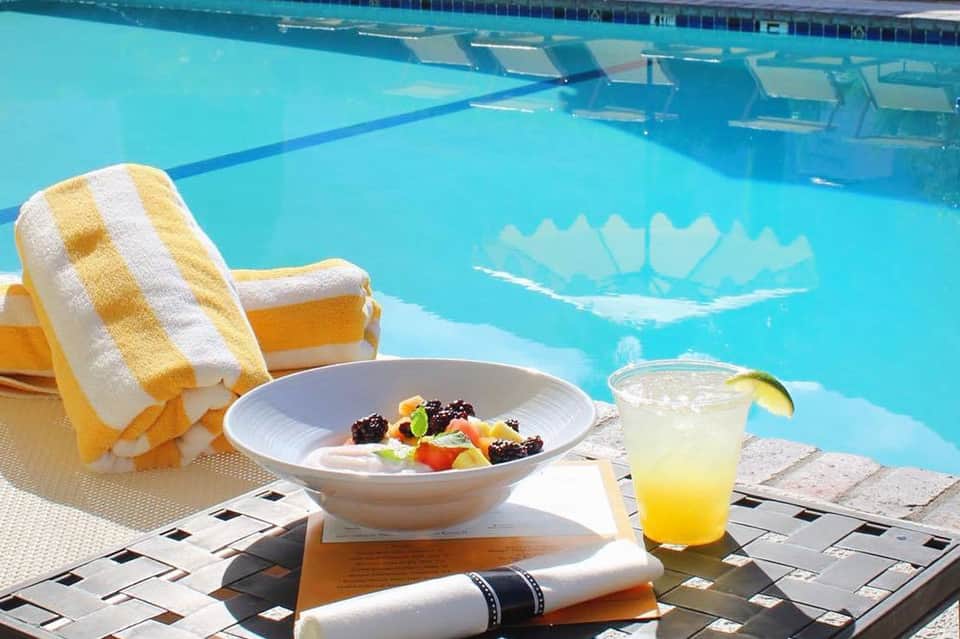 Poolside lounging with yellow towel, fresh fruit bowl, and tropical drink