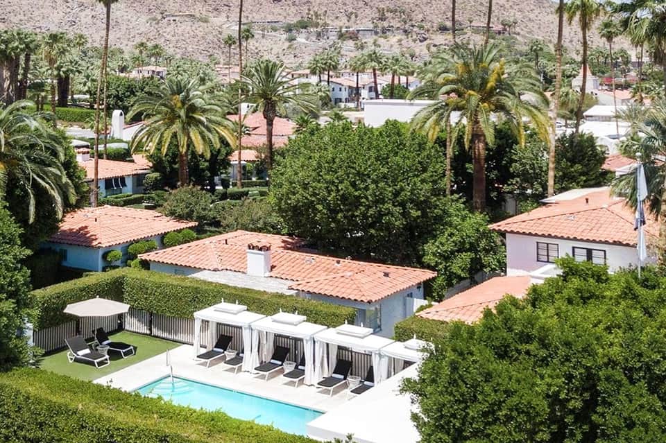 Aerial view of residential compound with small pool, cabanas, palm trees, and terra cotta roofs
