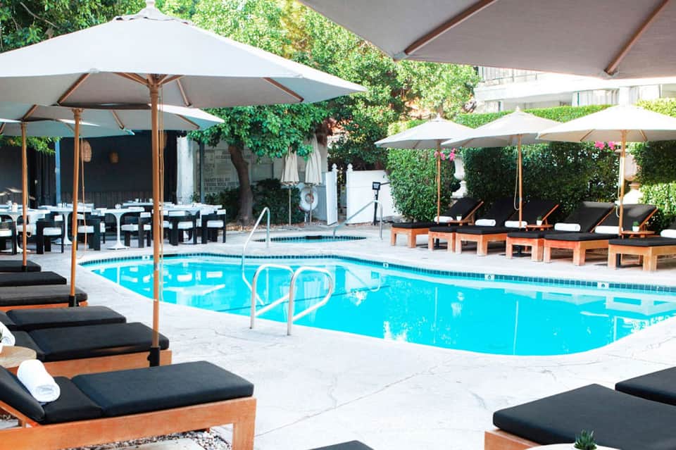 Resort pool surrounded by lounge chairs, white umbrellas, and ivy-covered walls