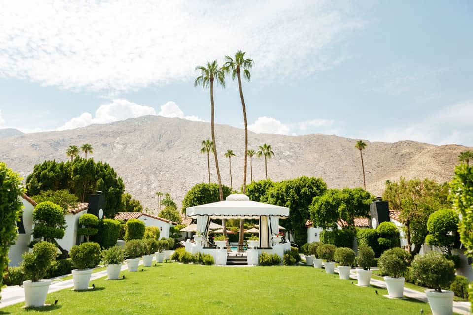 Elegant white gazebo on manicured lawn with desert mountains and palm trees in background