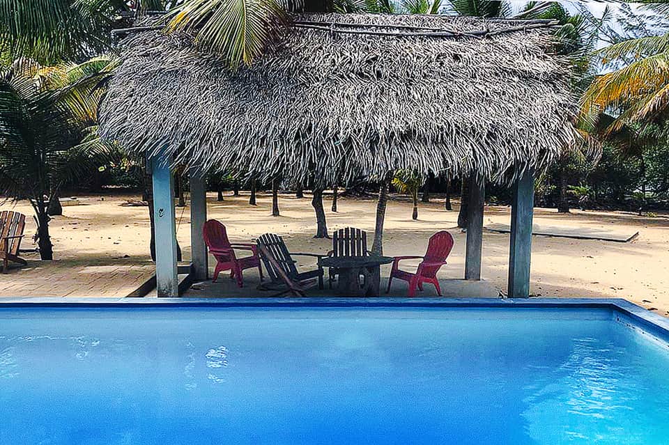 Tropical beach resort with thatched-roof cabana, lounge chairs, and turquoise pool