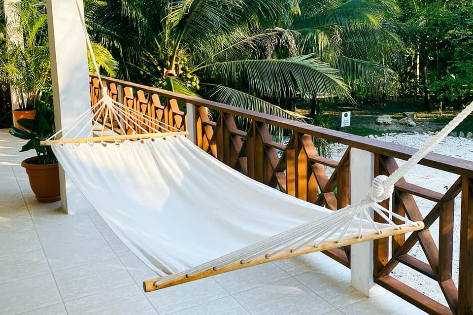 White hammock on wooden deck overlooking tropical lagoon and palm trees