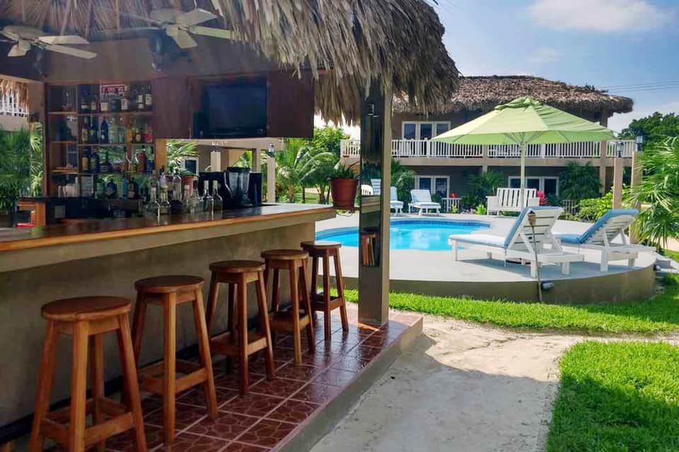 Tropical resort pool bar with thatched roof and wooden barstool seating