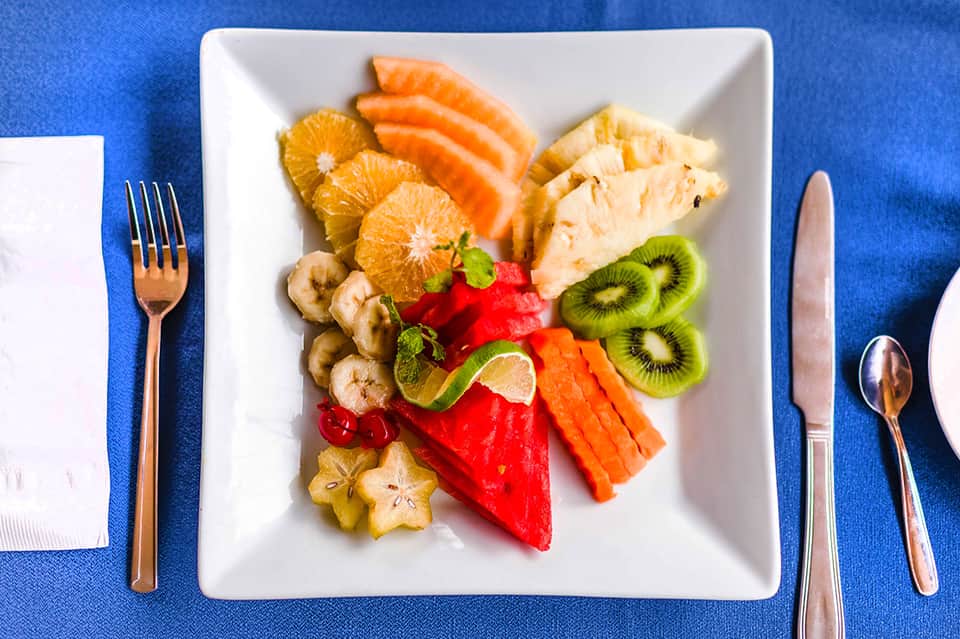 Elegant fruit and protein plate with citrus, kiwi, and salmon on blue tablecloth