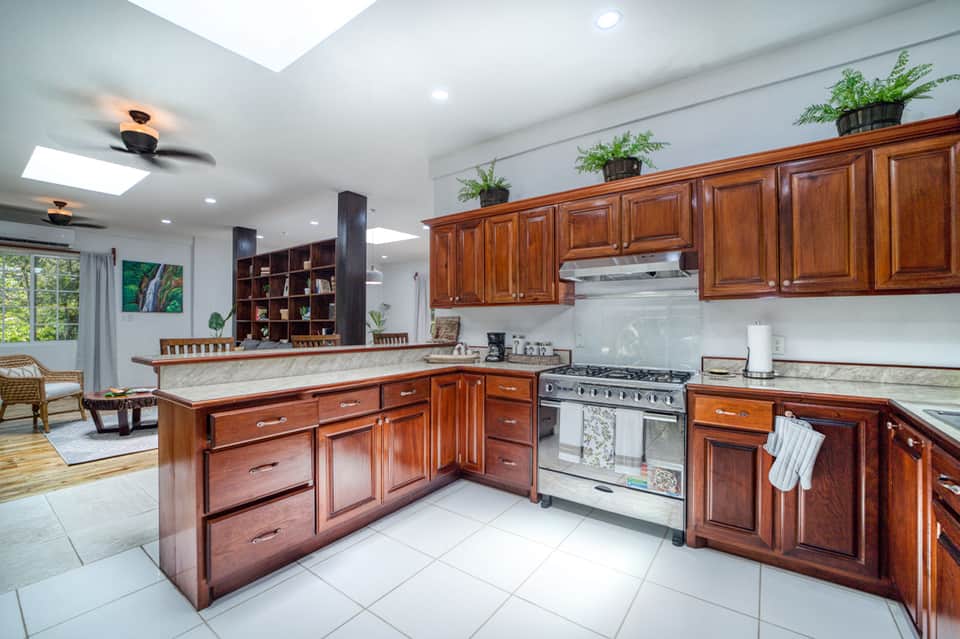 Modern kitchen with wood cabinetry, marble countertops, stainless steel appliances, and skylights