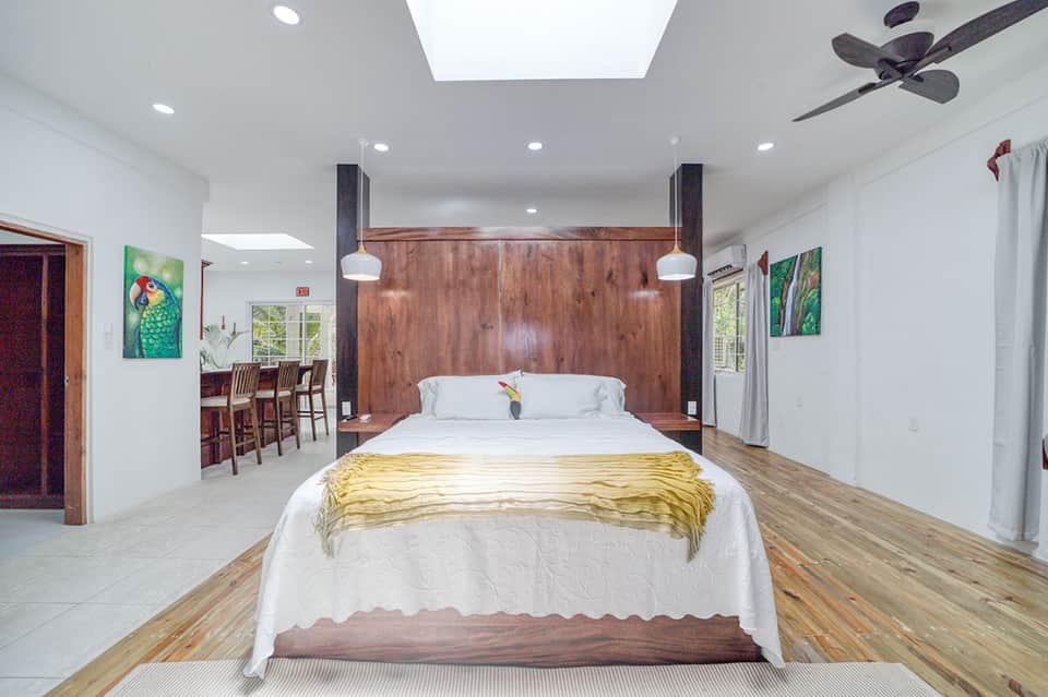 Spacious modern bedroom with wooden accent wall, king bed, and open floor plan with kitchen area