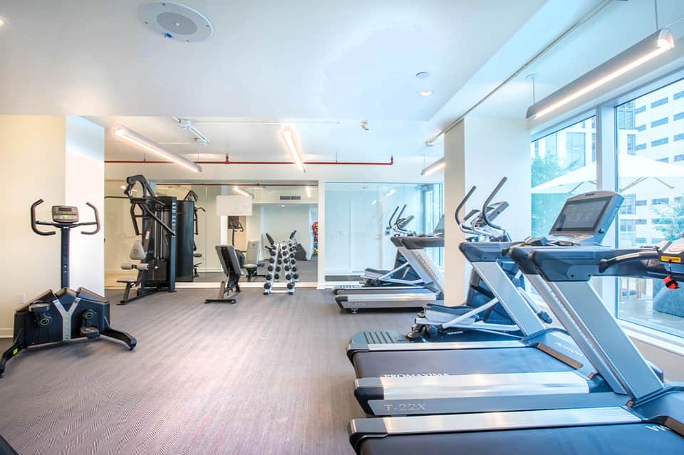 Bright modern fitness center with treadmills, exercise bikes, and city views
