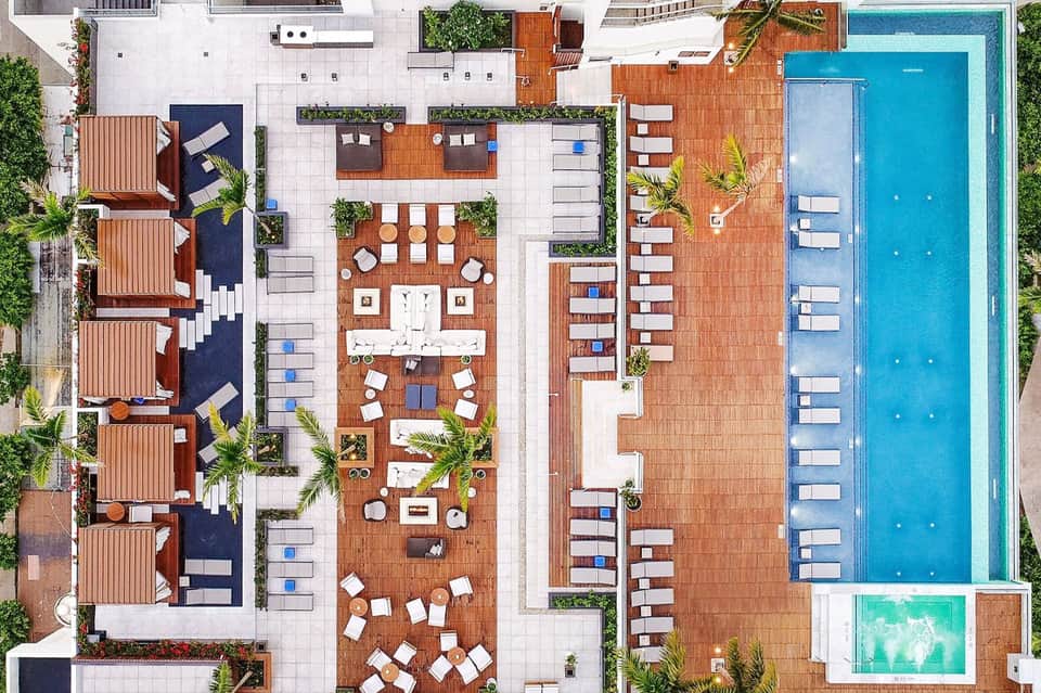 Aerial view of resort courtyard with pool, lounge chairs, and wooden deck area
