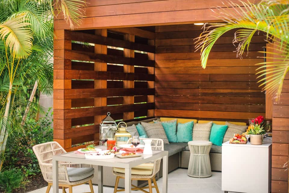 Outdoor patio with wooden pergola, built-in bench seating, and turquoise accent pillows