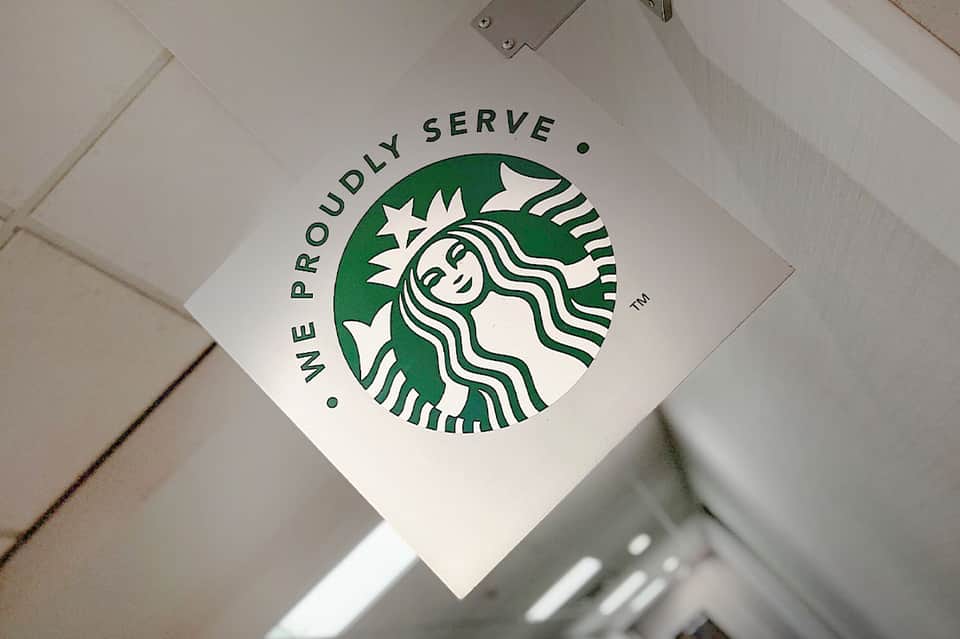 Starbucks logo with 'We Proudly Serve' text on ceiling