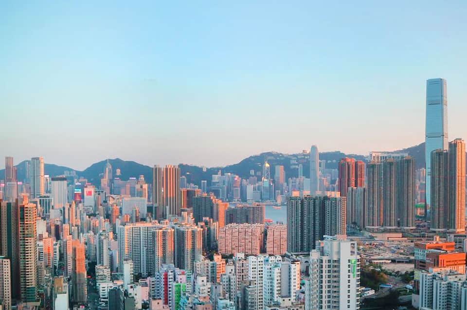 Hong Kong skyline at sunset with dense high-rise buildings and Victoria Harbor
