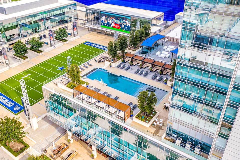 Aerial view of luxury resort with pool, fitness field, and modern high-rise buildings
