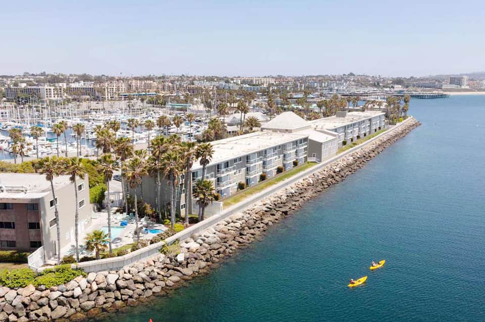 Aerial view of waterfront resort with palm trees, boats, and coastal marina