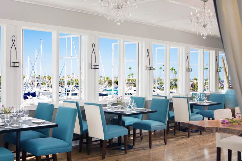 Upscale dining room with turquoise chairs, white trim windows overlooking marina