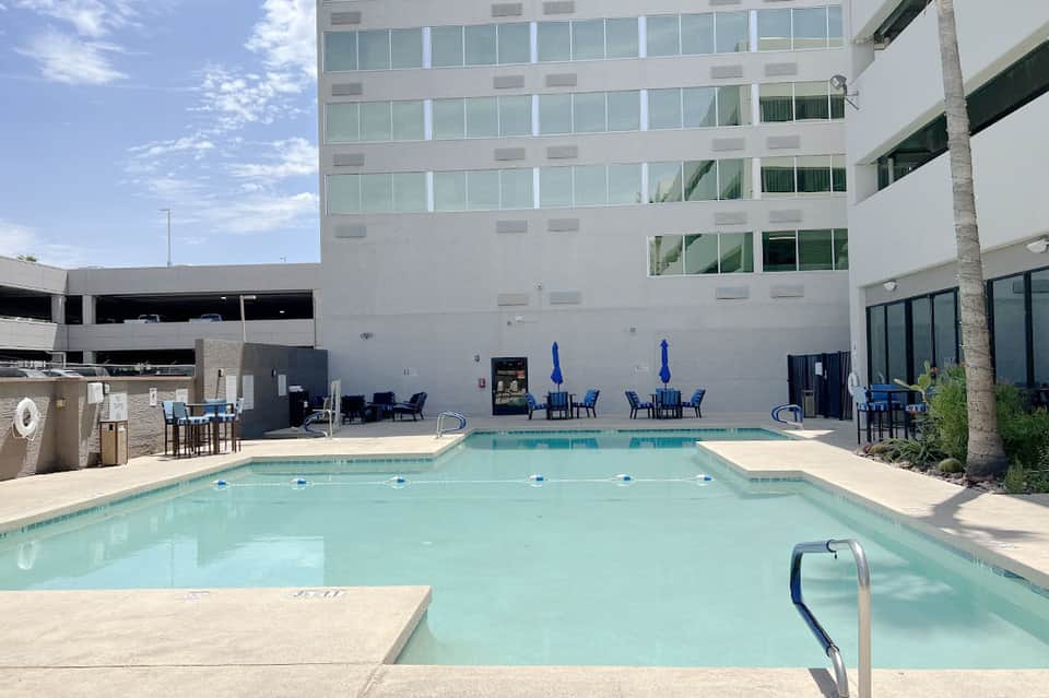 Rectangular lap pool with blue umbrellas and lounge chairs in modern hotel courtyard
