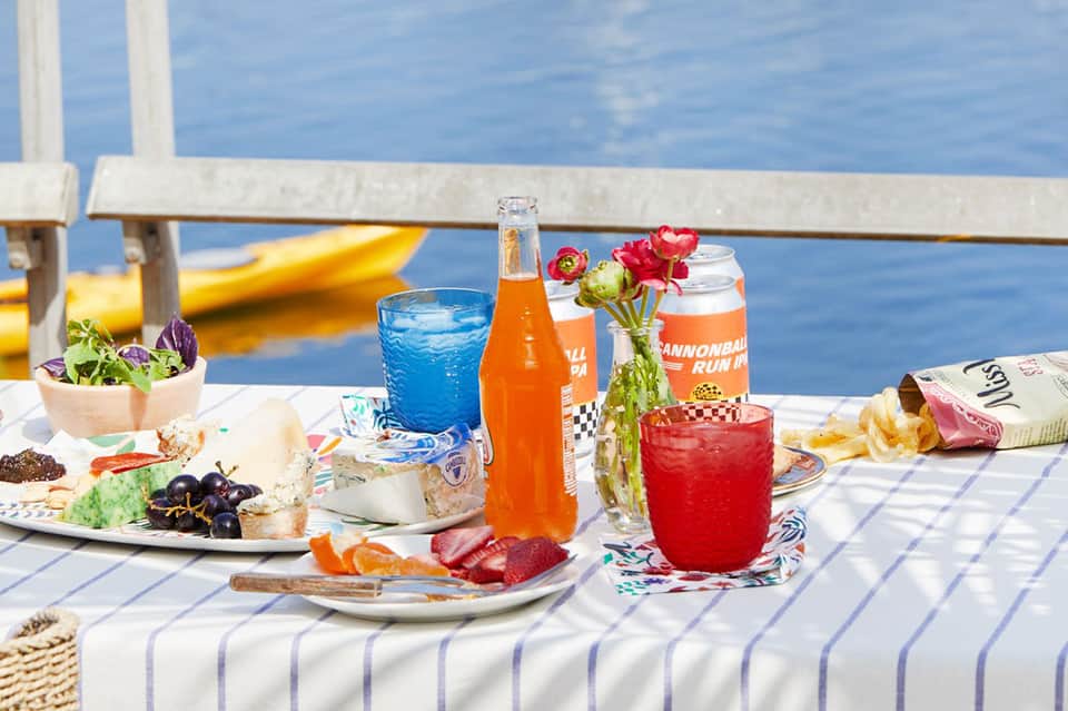 Beachside lunch table with beverages, snacks, flowers, and ocean view with yellow kayak