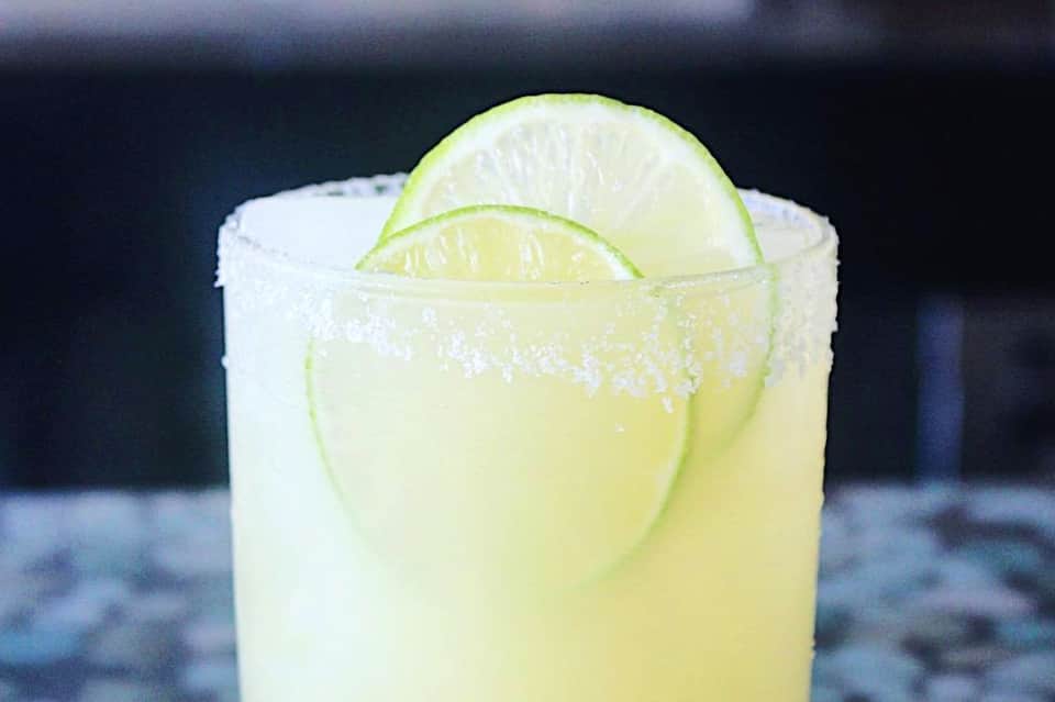Margarita cocktail with salt rim and lime slice on dark background