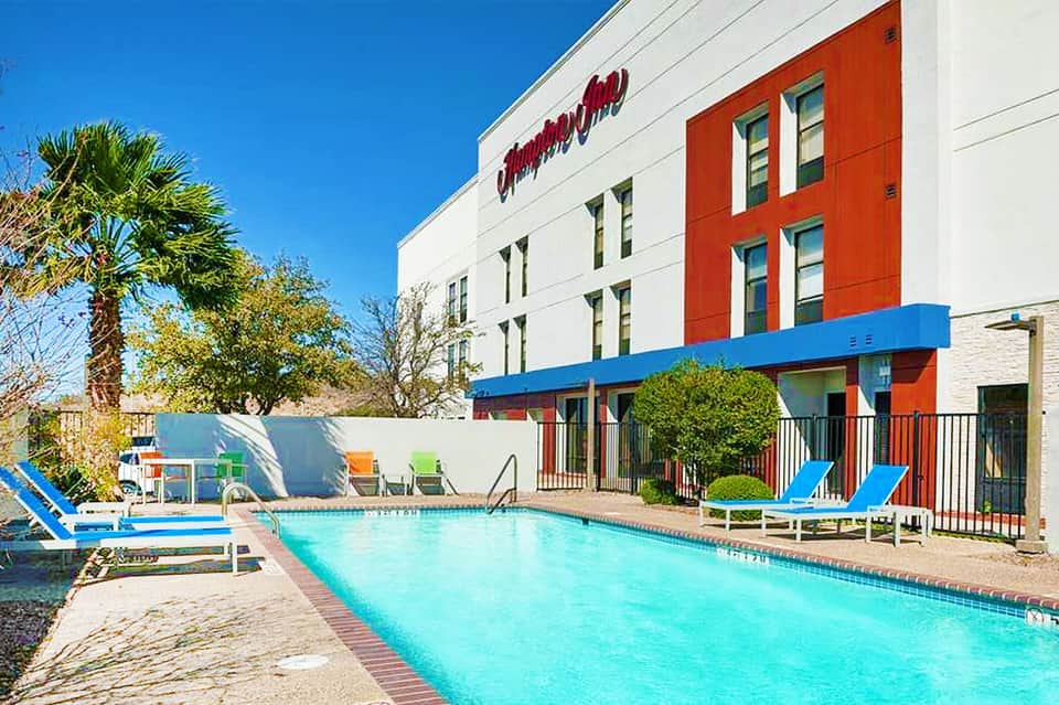 Modern hotel with red accent wall and bright blue swimming pool