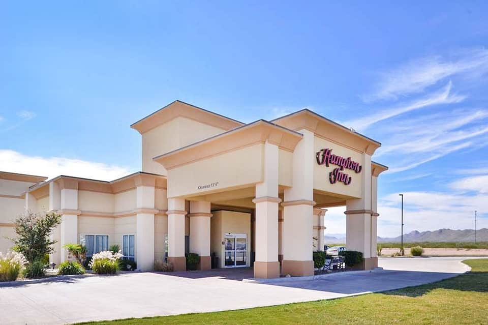 Hampton Inn exterior with tan facade and purple signage in desert landscape