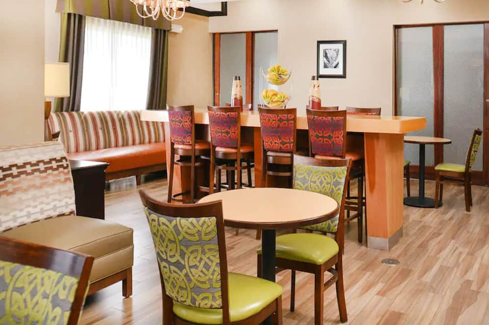 Hotel lounge with striped orange sofa, colorful patterned chairs, round tables, and modern hospitality furnishings