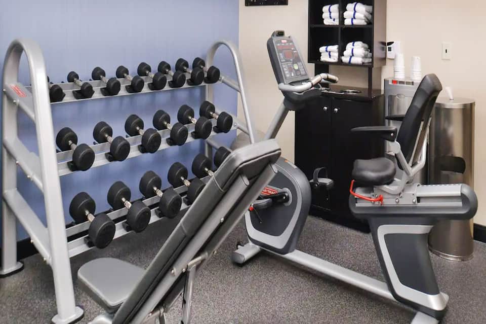 Modern fitness center with dumbbell rack, exercise bikes, and gym equipment in well-lit room