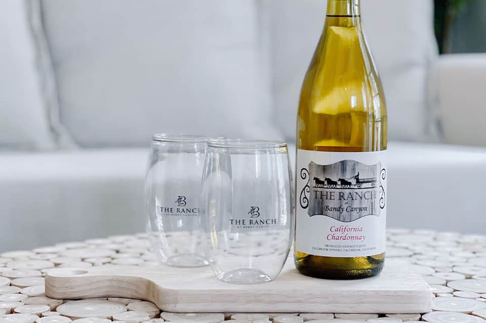 Branded wine glasses and California Chardonnay bottle on white surface