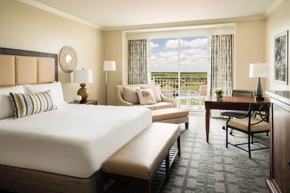 Elegant hotel bedroom with ocean view balcony, neutral tones, and contemporary furnishings