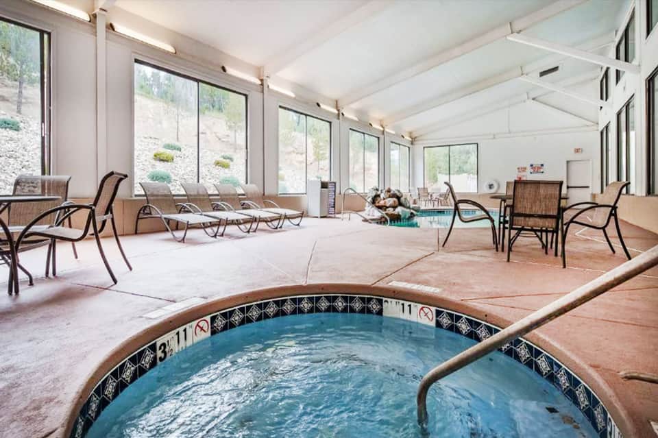 Indoor pool area with lounge chairs, large windows, and mountain views in background
