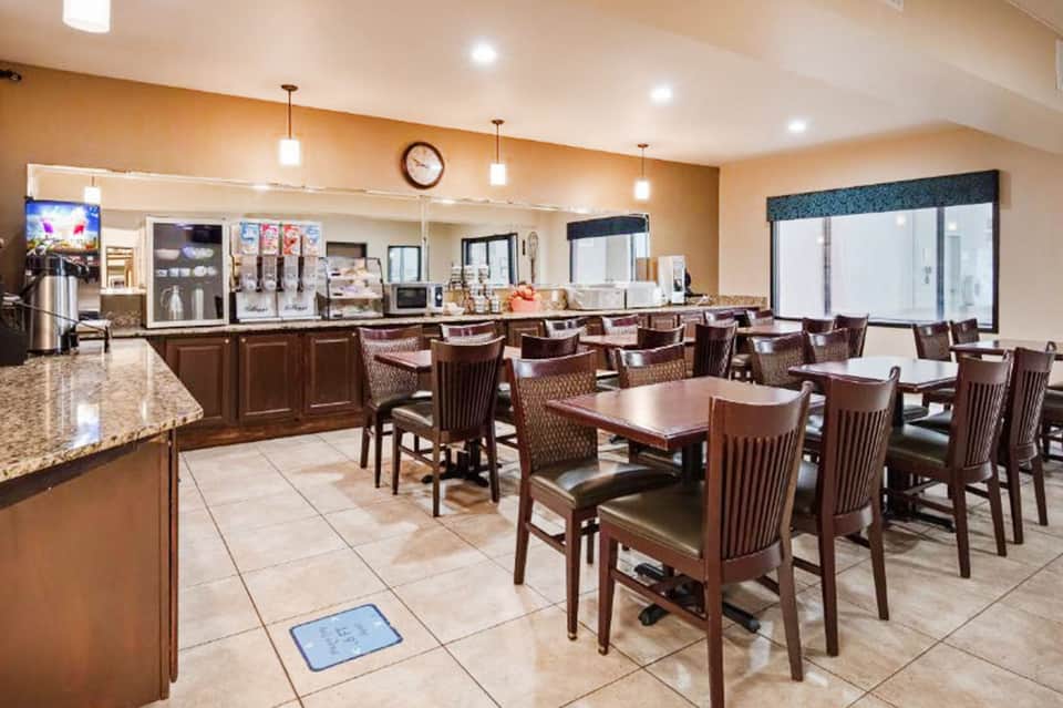 Hotel breakfast area with brown wood furnishings, counter service, and dining tables