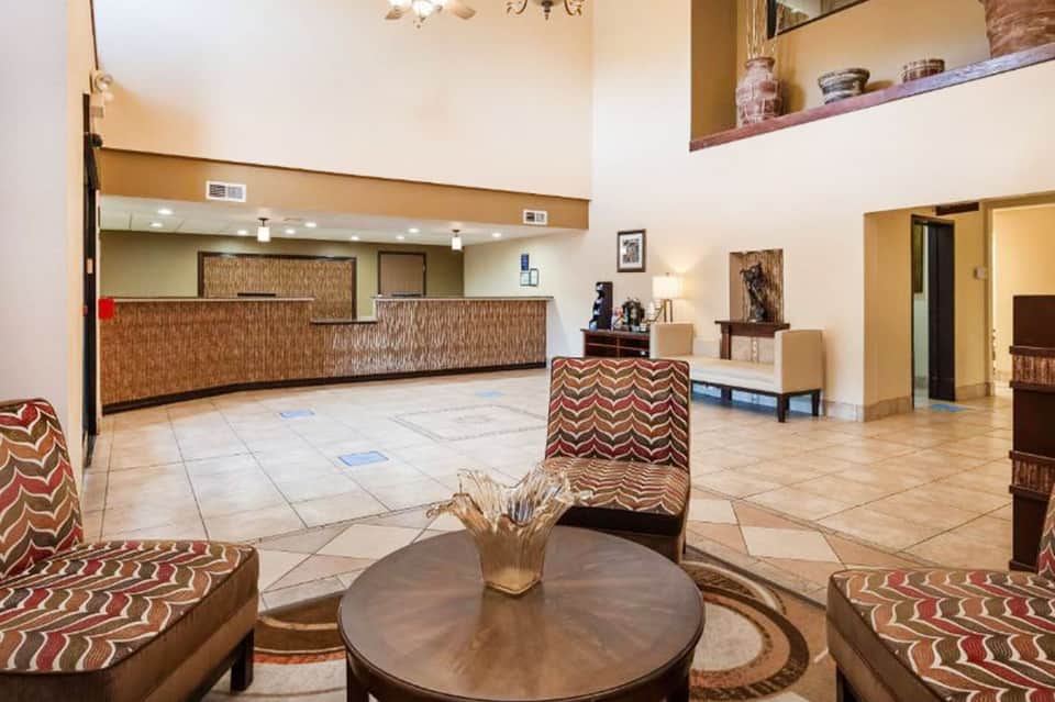 Hotel lobby with brick accent wall, round wooden table, patterned seating, and reception desk