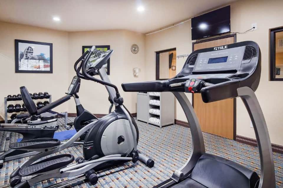 Fitness center with treadmill and exercise bike, dumbbells, and TV mounted on wall