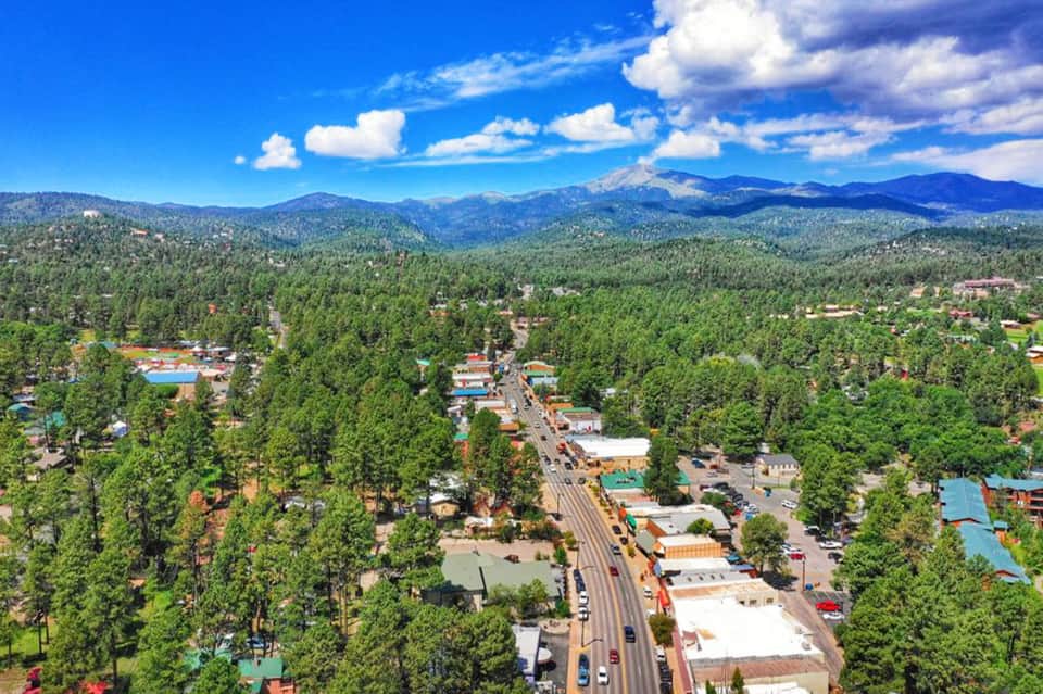 Aerial view of mountain resort town with colorful pools and surrounding forest peaks
