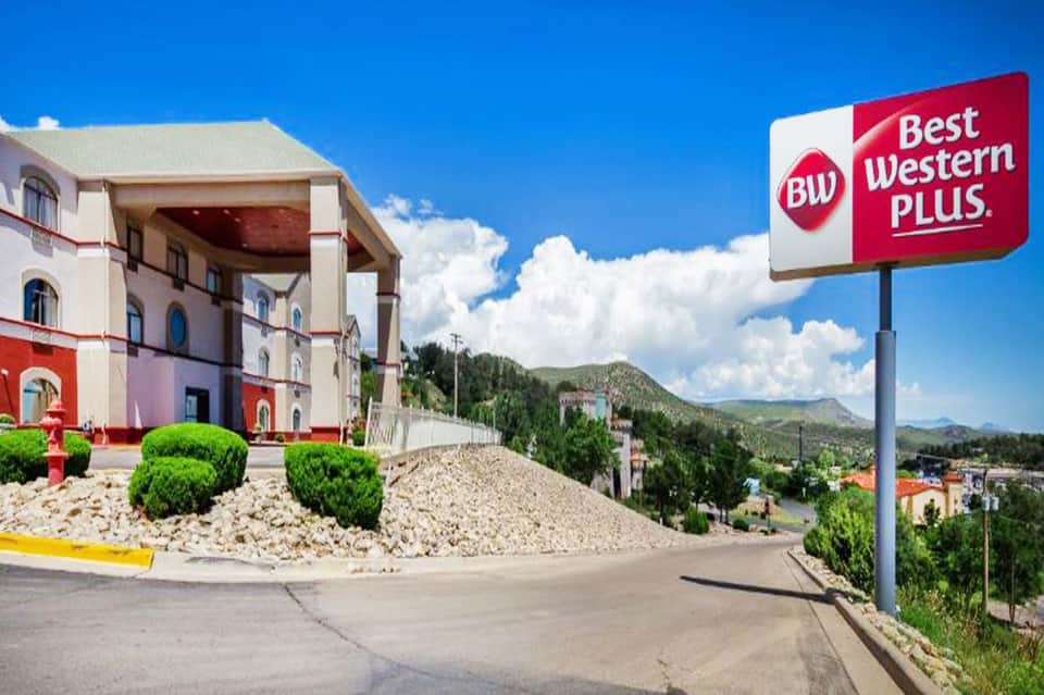 Best Western Plus hotel exterior with pink colonial architecture set against mountains under clear blue sky