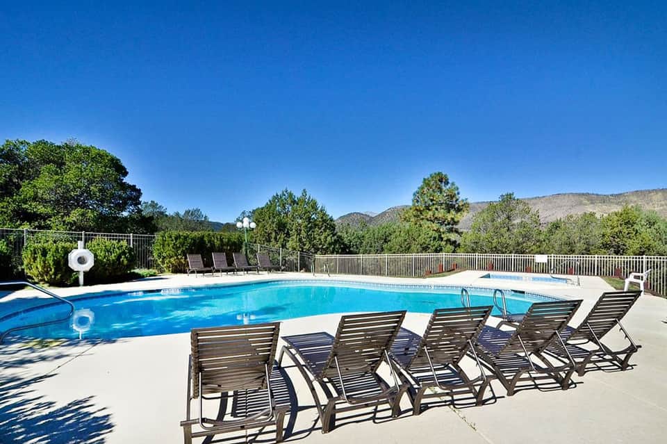 Resort pool surrounded by lounge chairs with mountain views and clear blue sky