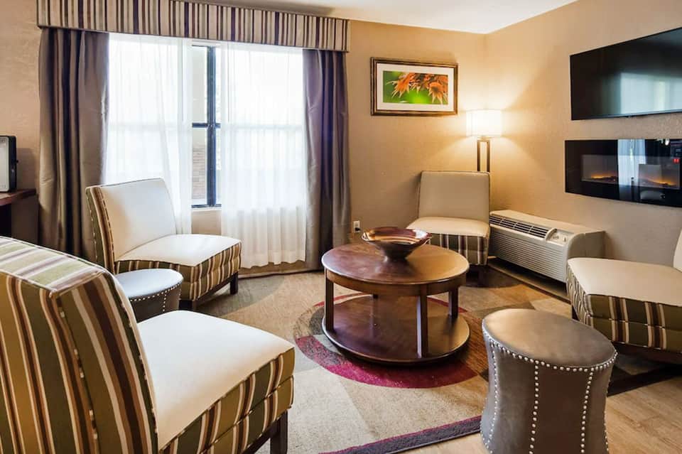 Elegant hotel suite living room with striped upholstered chairs, round coffee table, and fireplace