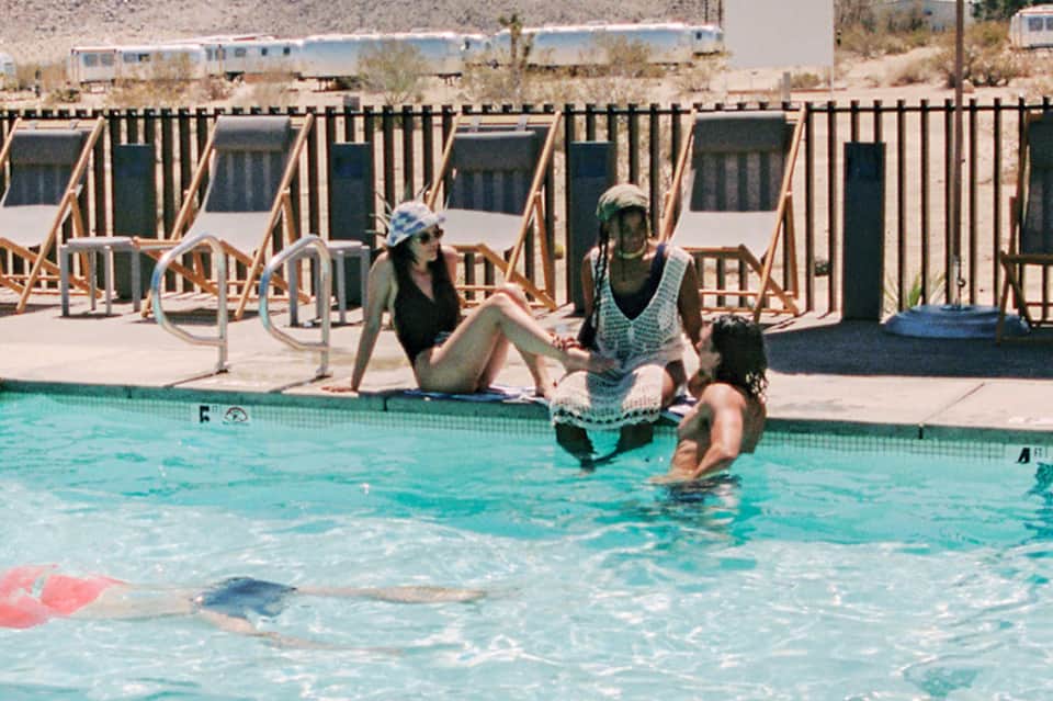 Guests enjoying pool time at desert resort with lounge chairs and palm trees