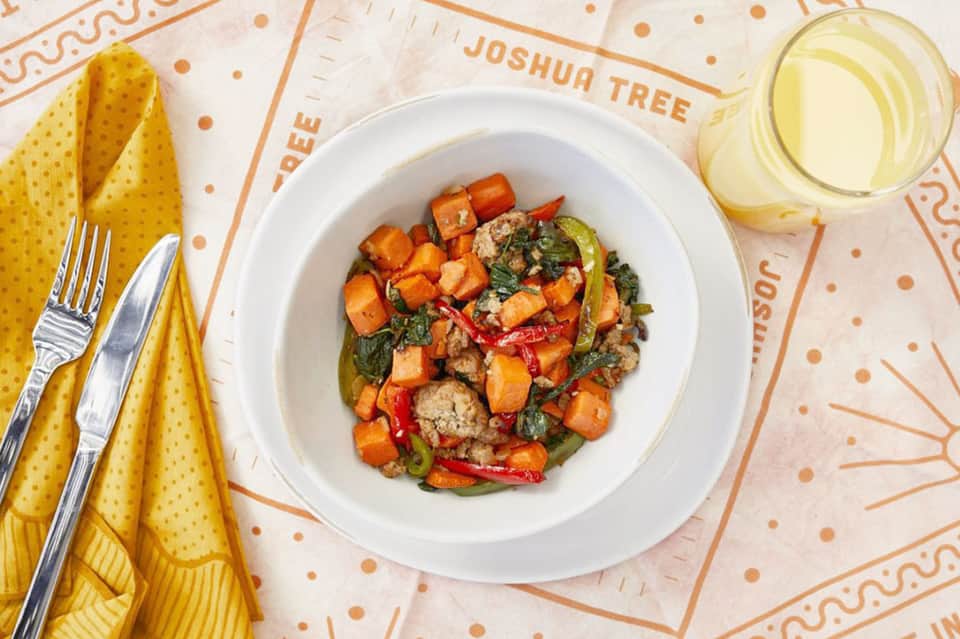 Plated dining with roasted vegetables and greens on branded tablecloth at restaurant