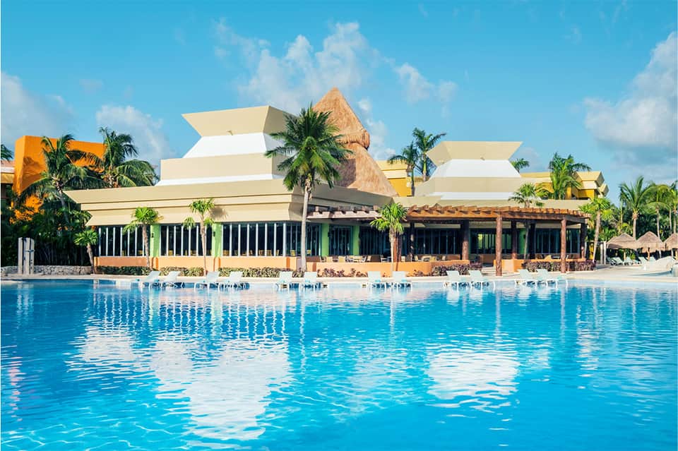 Tropical beachfront resort with thatched roof buildings and palm trees