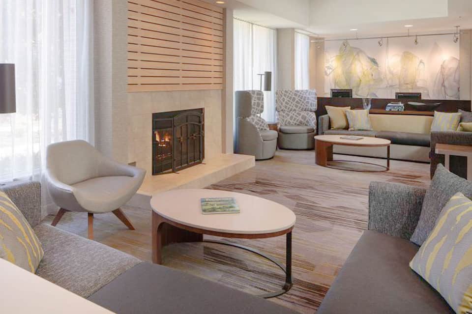 Modern lounge area with fireplace, neutral seating, and floor-to-ceiling windows