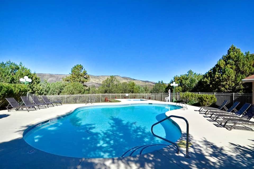 Outdoor swimming pool surrounded by lounge chairs and mountains in background