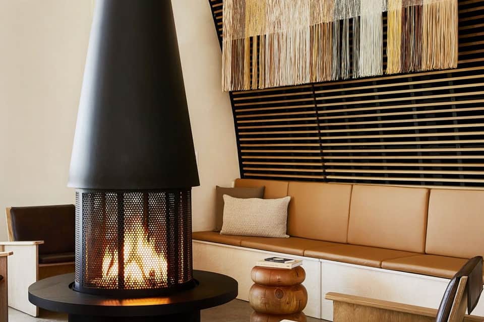 Modern lounge with fireplace, geometric wall art, tan leather sofa, and contemporary furnishings