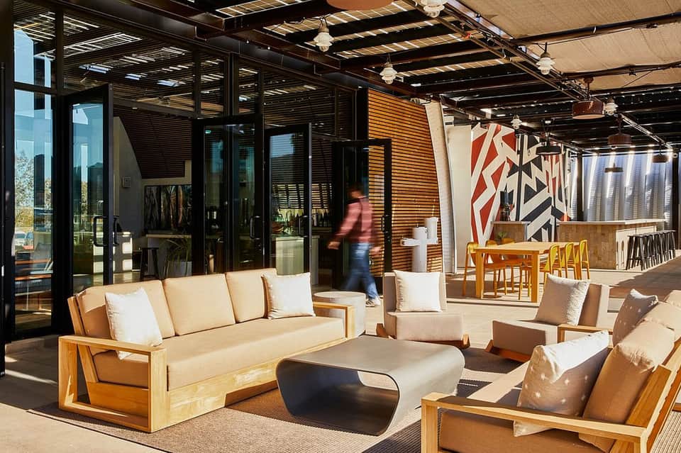 Modern rooftop terrace with wooden lounge seating, shaded canopy, and contemporary decor