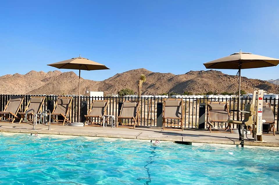Resort pool with lounge chairs and umbrellas against desert mountain landscape