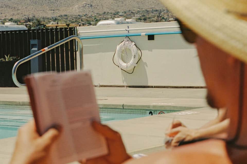 Person holding drink overlooking resort pool and rooftop area