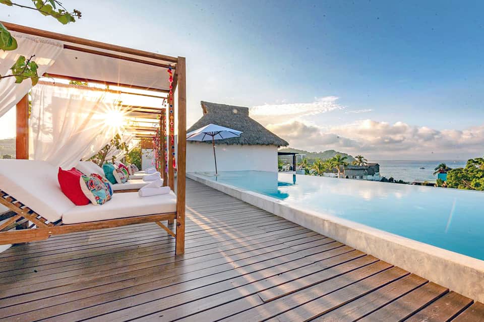 Luxury infinity pool overlooking the ocean with canopy bed lounge on wooden deck