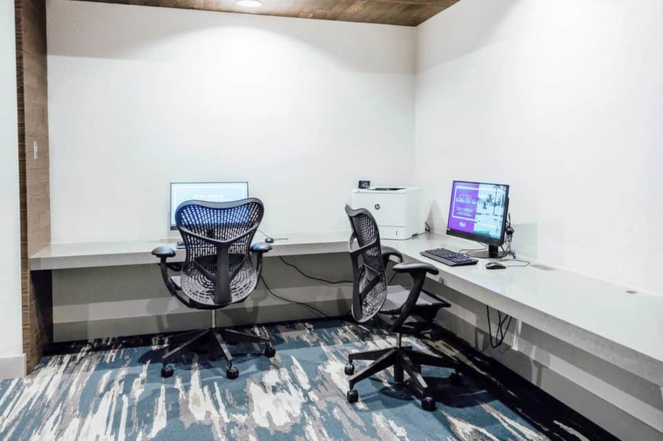 Modern business center with dual desk workstations, ergonomic chairs, and computer monitors