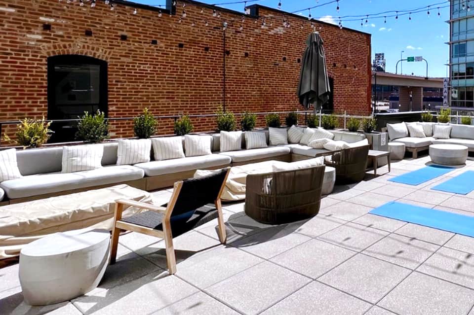 Urban rooftop lounge with modern seating, brick building backdrop, and blue accent tiles