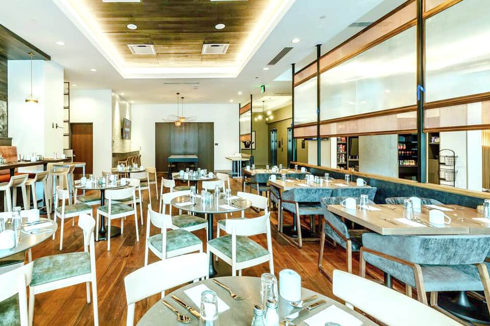 Modern dining room with white chairs, wood accents, and floor-to-ceiling windows